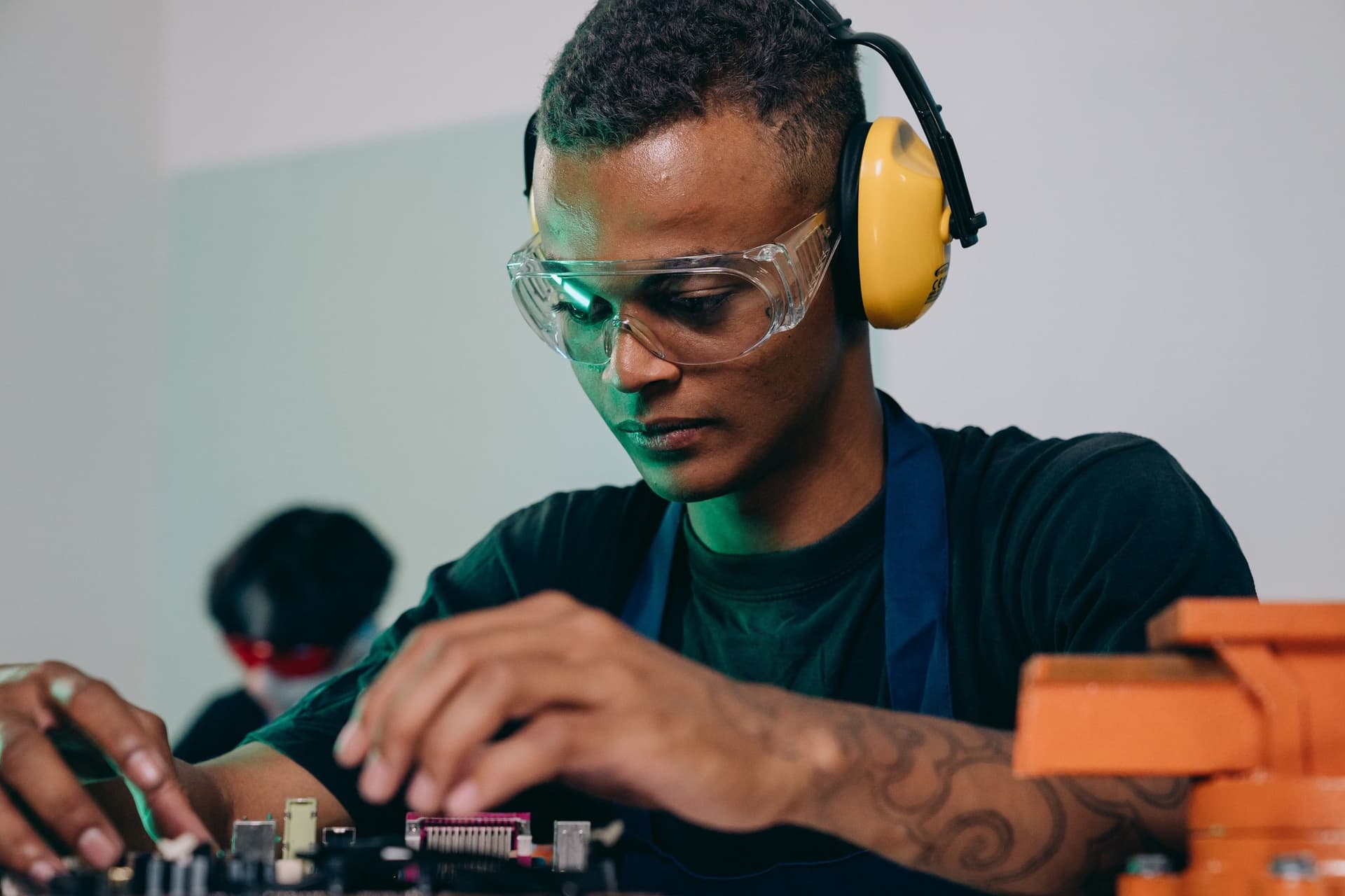 Technician in safety glasses and ear protection working on a machine