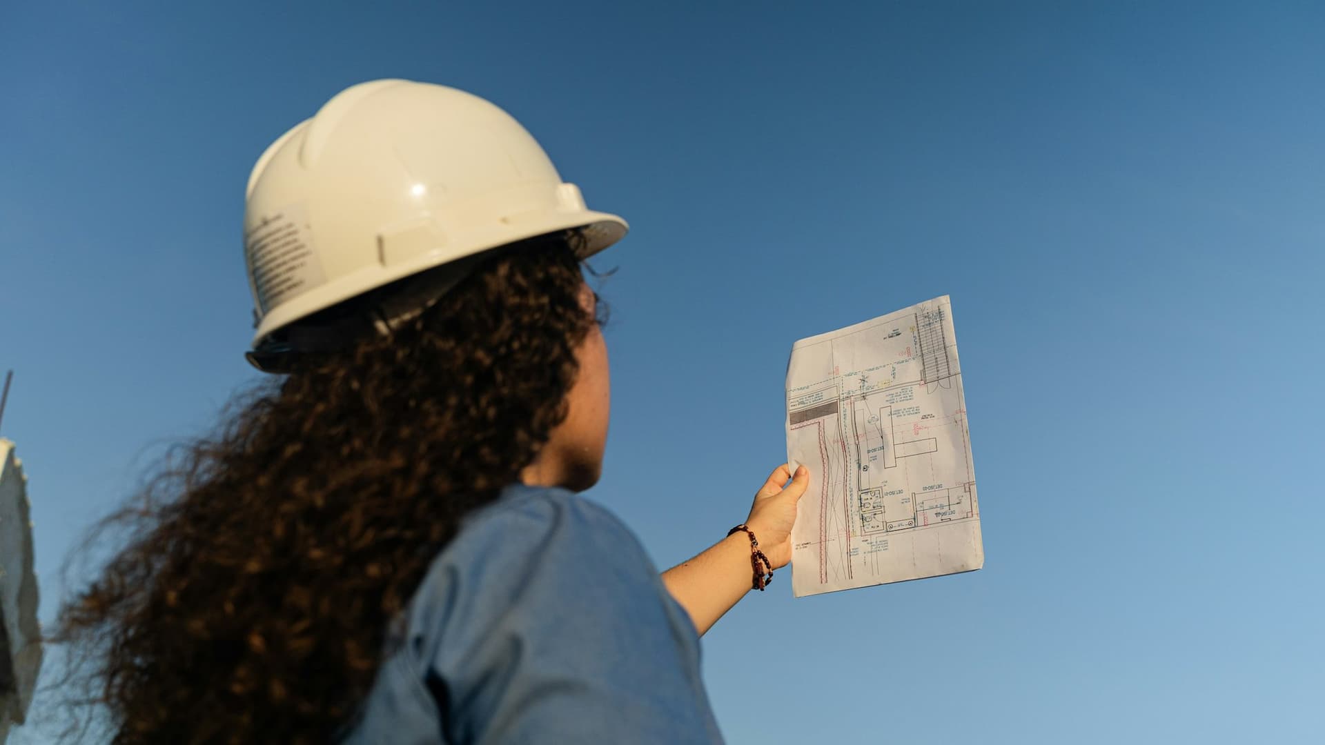 Engineer in a white hard hat checking construction plans