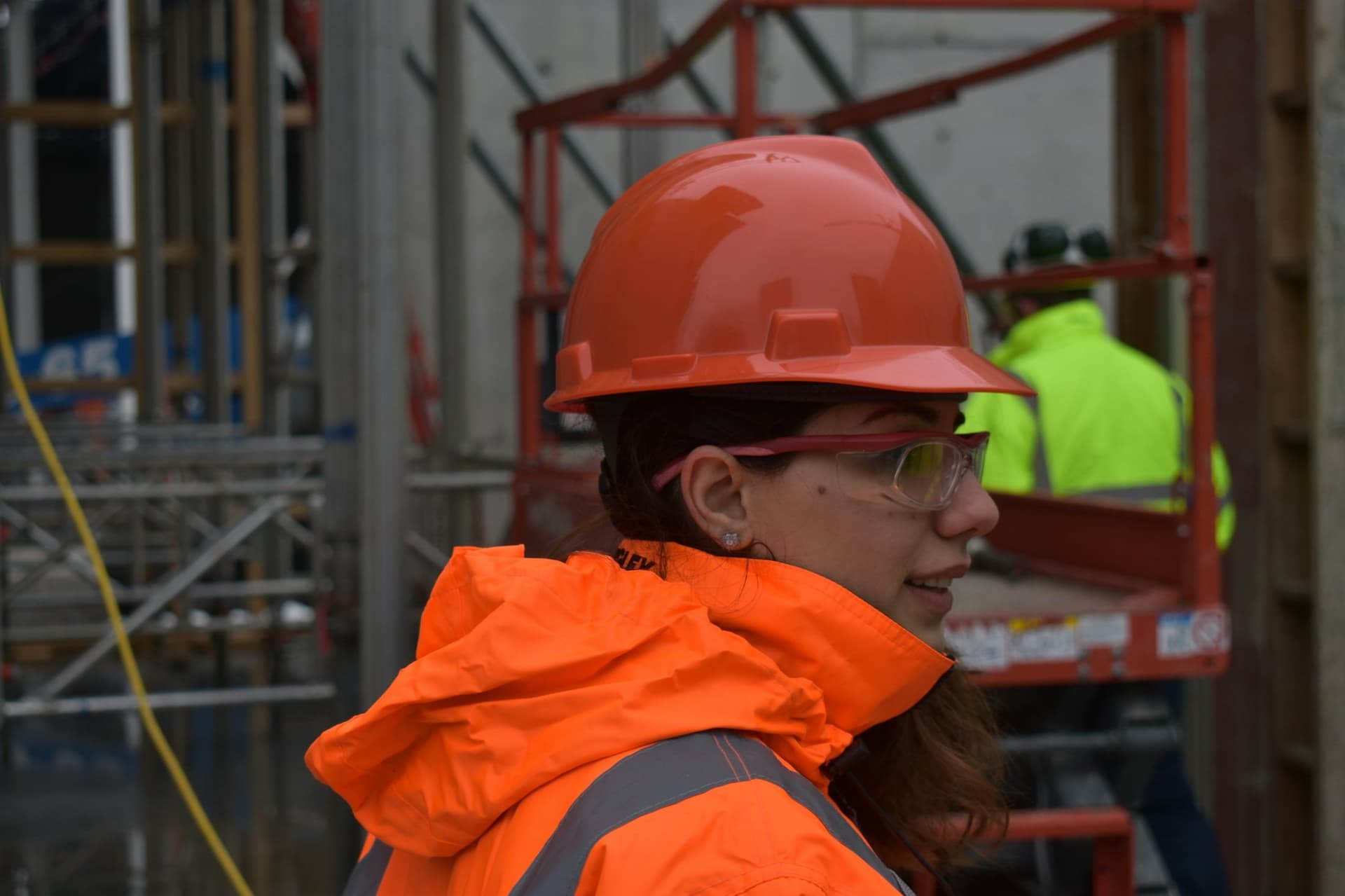 Engineer in an orange hard hat and safety glasses inspecting an industrial site