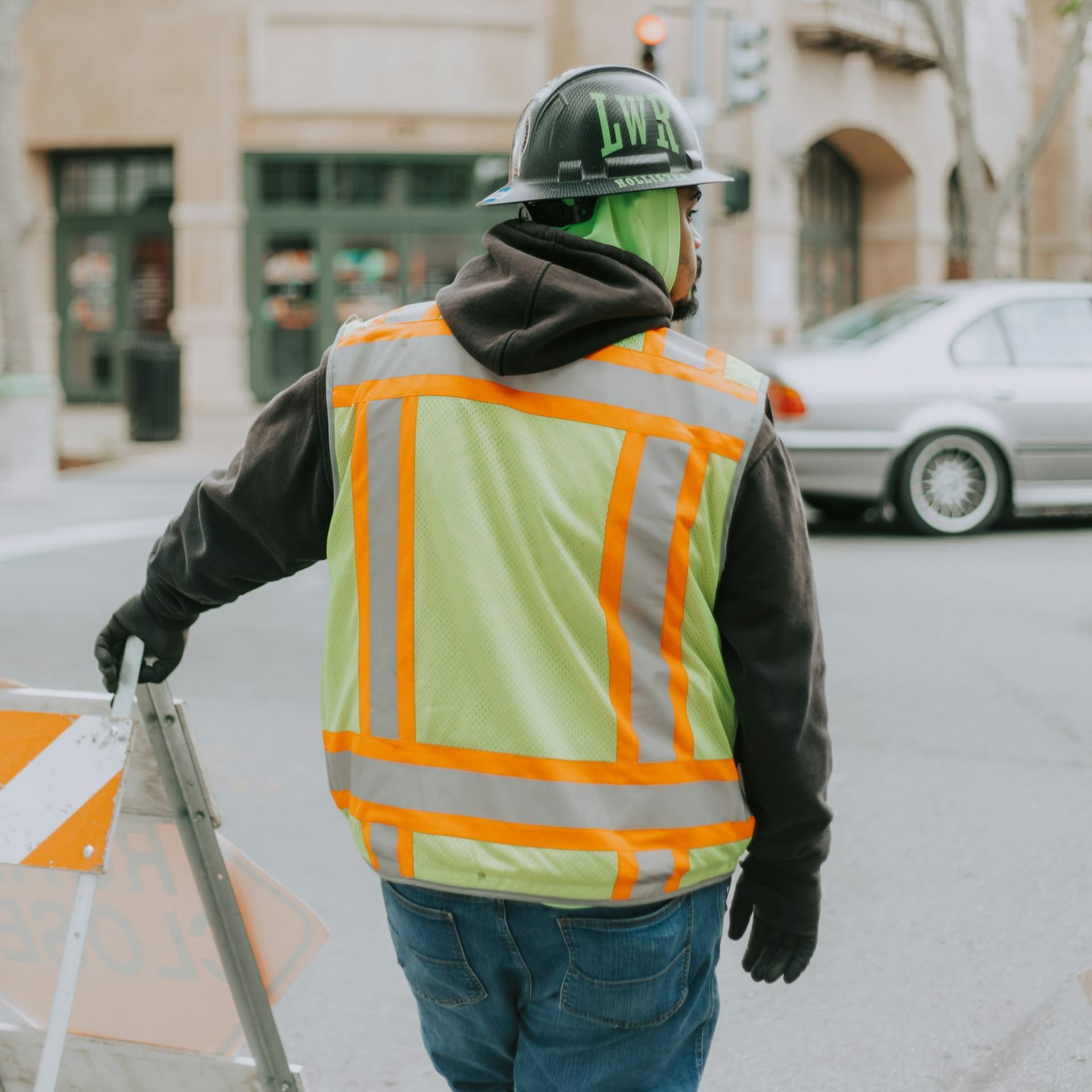 Crew member in a safety vest setting up traffic control on a city street